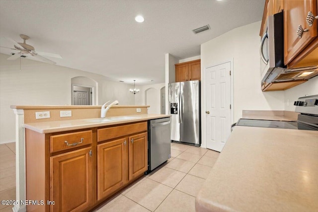 kitchen with ceiling fan with notable chandelier, sink, a kitchen island with sink, light tile patterned floors, and stainless steel appliances