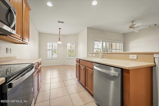 kitchen with light tile patterned flooring, sink, appliances with stainless steel finishes, a kitchen island, and pendant lighting