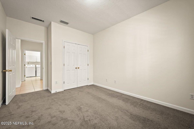 unfurnished bedroom featuring separate washer and dryer, carpet, a textured ceiling, and a closet