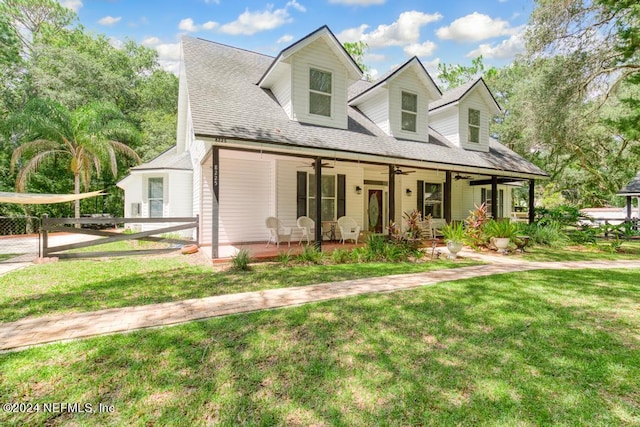 view of front of house with a porch, a shingled roof, a front yard, fence, and ceiling fan