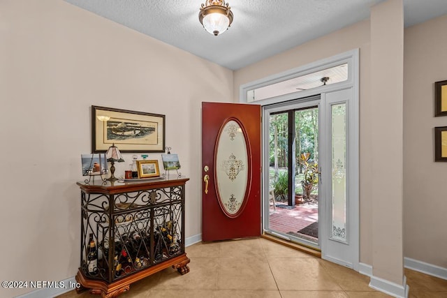 tiled foyer entrance featuring baseboards and a textured ceiling