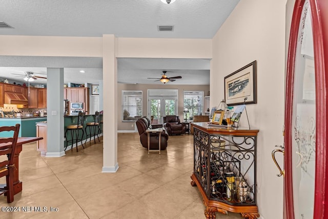 living area with visible vents, ceiling fan, a textured ceiling, and baseboards