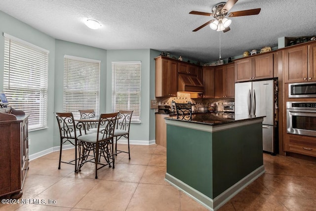 kitchen featuring dark countertops, a healthy amount of sunlight, stainless steel appliances, and decorative backsplash