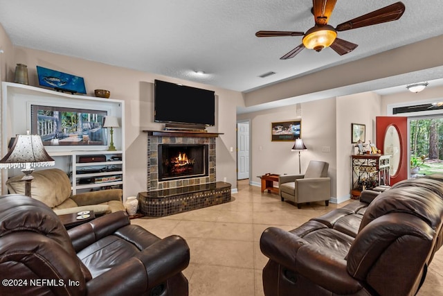 living room with a ceiling fan, baseboards, visible vents, tile patterned floors, and a tiled fireplace