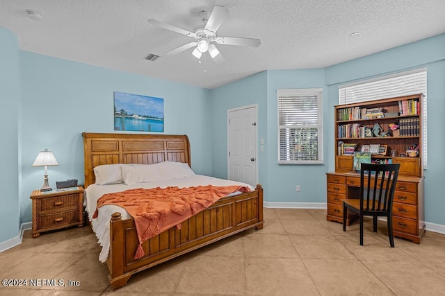 bedroom with a textured ceiling, light tile patterned flooring, visible vents, and baseboards