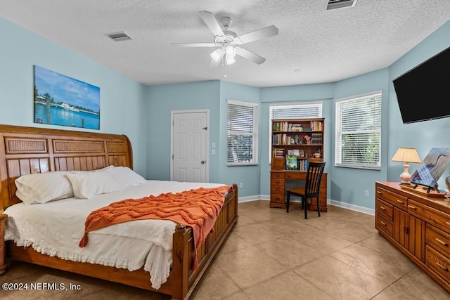 bedroom with a ceiling fan, baseboards, visible vents, and a textured ceiling