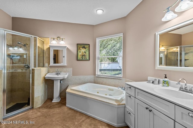 full bath featuring two sinks, a tub with jets, tile patterned flooring, a textured ceiling, and a shower stall