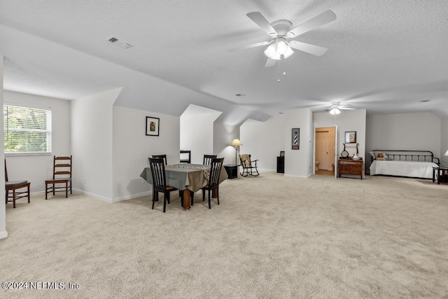 carpeted dining space with lofted ceiling, a textured ceiling, a ceiling fan, visible vents, and baseboards