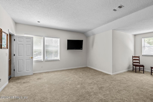 carpeted empty room featuring visible vents, a textured ceiling, and baseboards