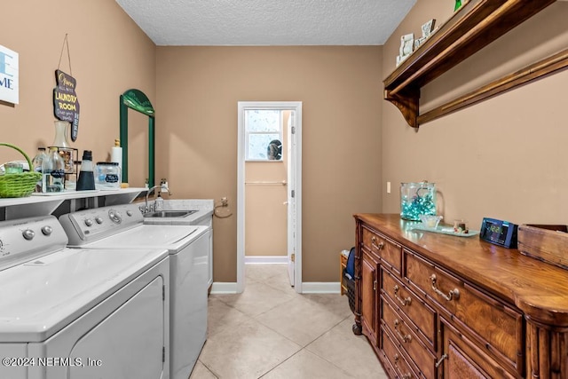 laundry room featuring washer and clothes dryer, light tile patterned floors, a sink, a textured ceiling, and baseboards