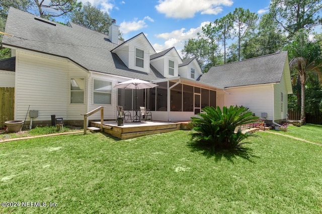 rear view of property featuring a shingled roof, fence, a sunroom, a yard, and a wooden deck