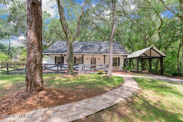 view of front of home with a gazebo, a shingled roof, a front yard, and fence