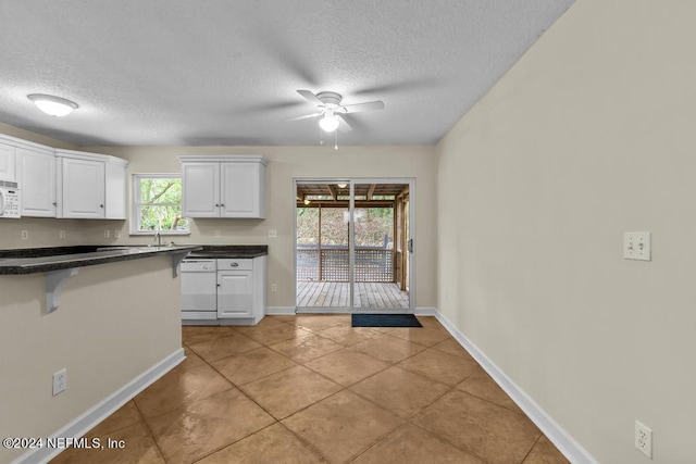 kitchen with ceiling fan, a breakfast bar area, white appliances, white cabinets, and dark countertops