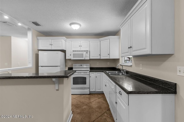 kitchen with tile patterned flooring, white appliances, a sink, visible vents, and white cabinetry