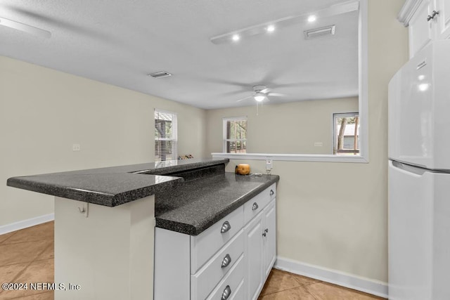 kitchen featuring freestanding refrigerator, a healthy amount of sunlight, visible vents, and dark countertops