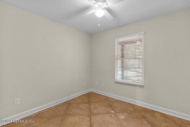 tiled empty room featuring a ceiling fan, a textured ceiling, and baseboards