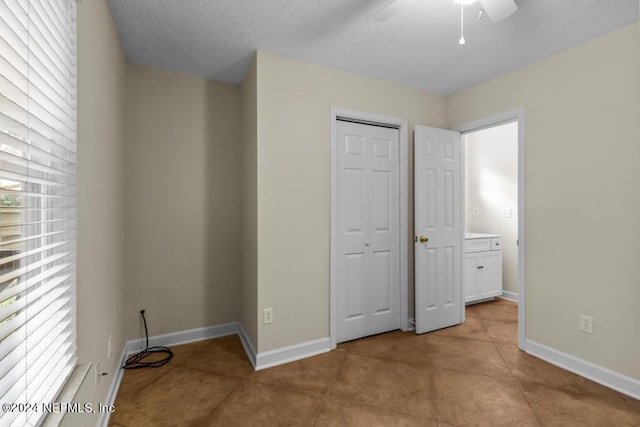 unfurnished bedroom featuring a textured ceiling, multiple windows, a closet, and baseboards