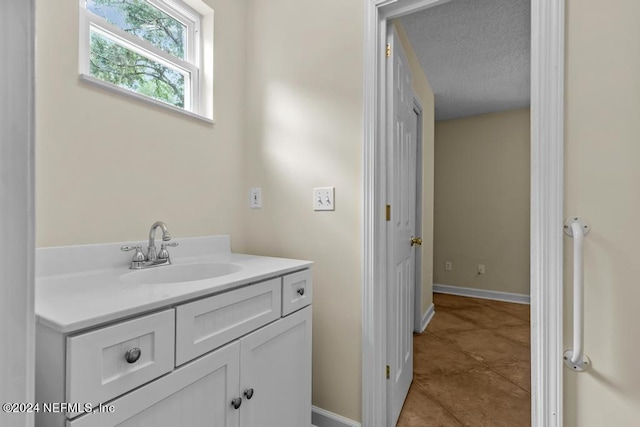 bathroom featuring a textured ceiling, vanity, baseboards, and tile patterned floors