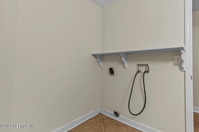 clothes washing area featuring laundry area, tile patterned flooring, hookup for a washing machine, and baseboards