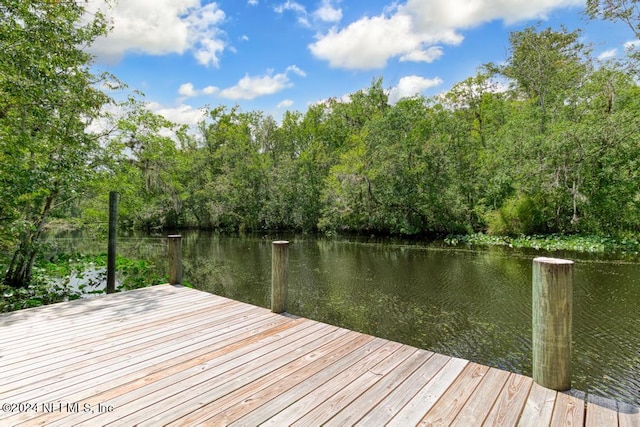 view of dock with a water view and a forest view