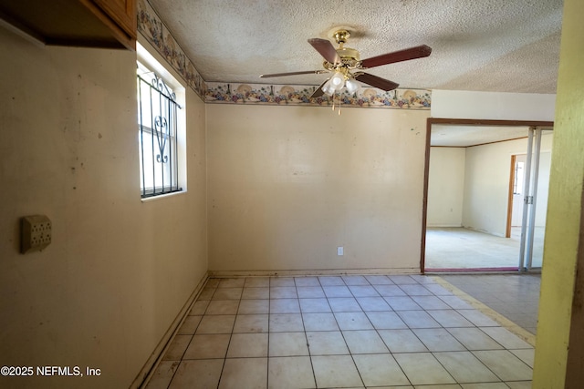 empty room featuring ceiling fan, a textured ceiling, and light tile patterned floors