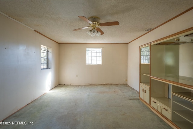 empty room featuring crown molding, light carpet, ceiling fan, and a textured ceiling