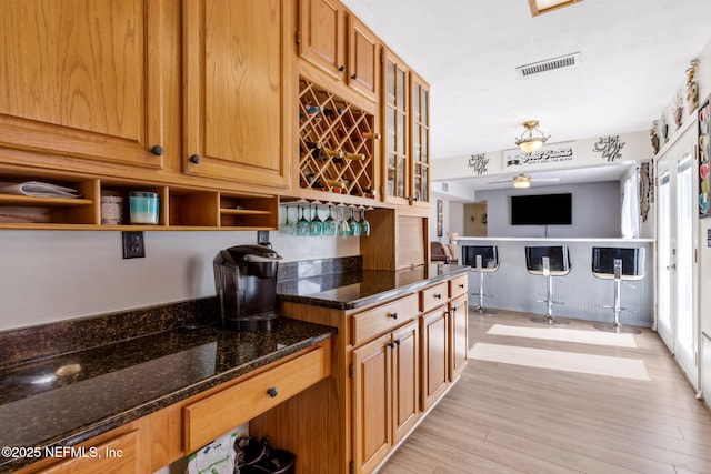 kitchen featuring ceiling fan, light wood-type flooring, and dark stone countertops