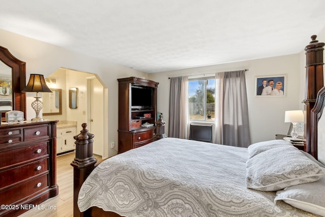 bedroom with ensuite bathroom and light wood-type flooring