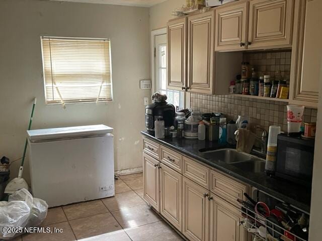 kitchen featuring fridge, sink, tasteful backsplash, and light tile patterned floors