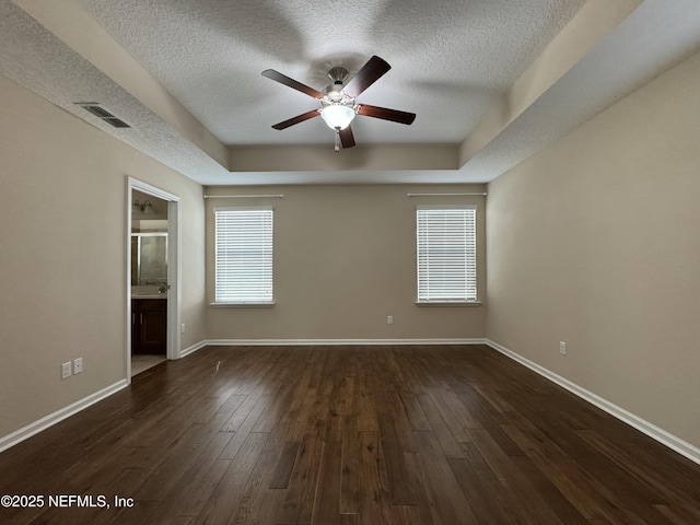 unfurnished room featuring ceiling fan, dark hardwood / wood-style flooring, a raised ceiling, and a textured ceiling