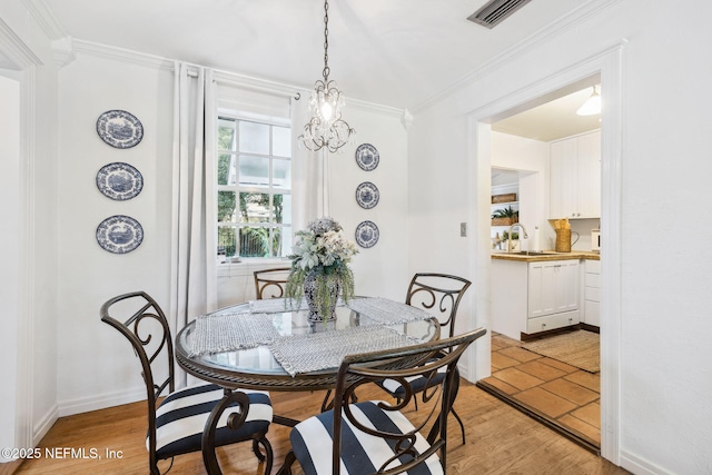 dining space featuring sink, ornamental molding, and light wood-type flooring