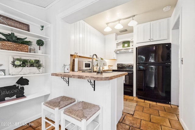 kitchen featuring sink, white cabinetry, a kitchen breakfast bar, kitchen peninsula, and black appliances