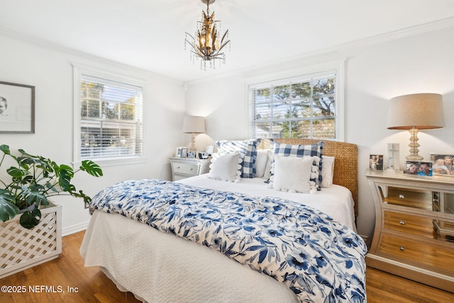 bedroom featuring an inviting chandelier, hardwood / wood-style flooring, and ornamental molding