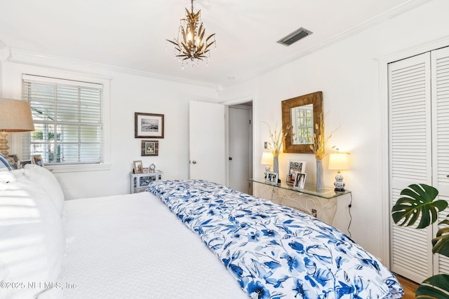 bedroom featuring crown molding, wood-type flooring, an inviting chandelier, and a closet