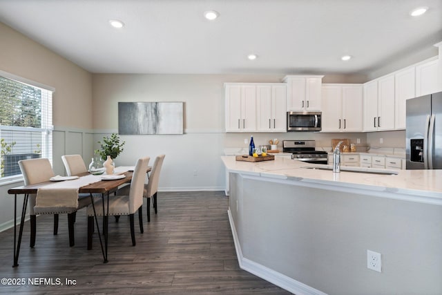 kitchen with appliances with stainless steel finishes, sink, white cabinets, and light stone counters