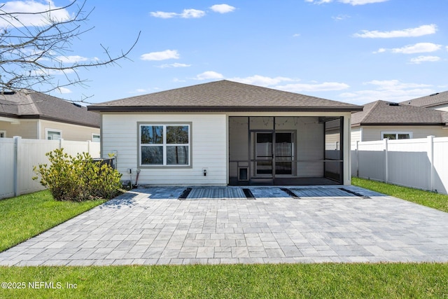 rear view of property featuring a yard, a sunroom, and a patio area