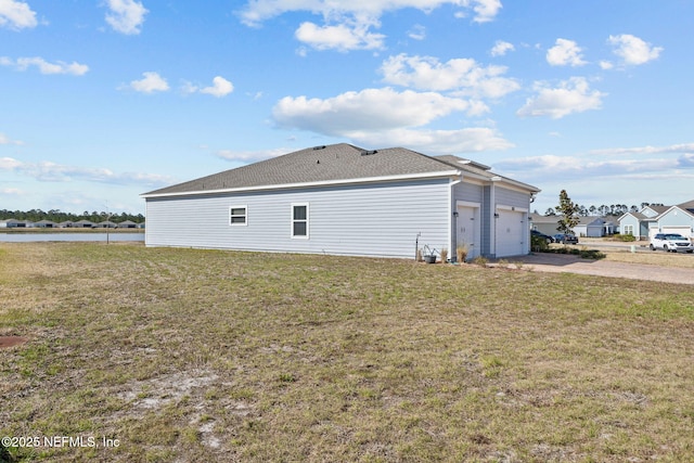 view of side of home featuring a garage, a water view, and a lawn