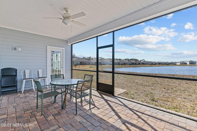 sunroom / solarium featuring a water view and ceiling fan