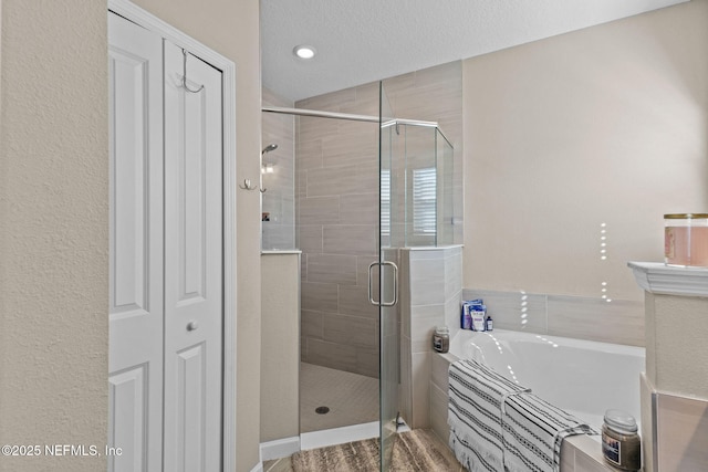 bathroom with shower with separate bathtub and a textured ceiling