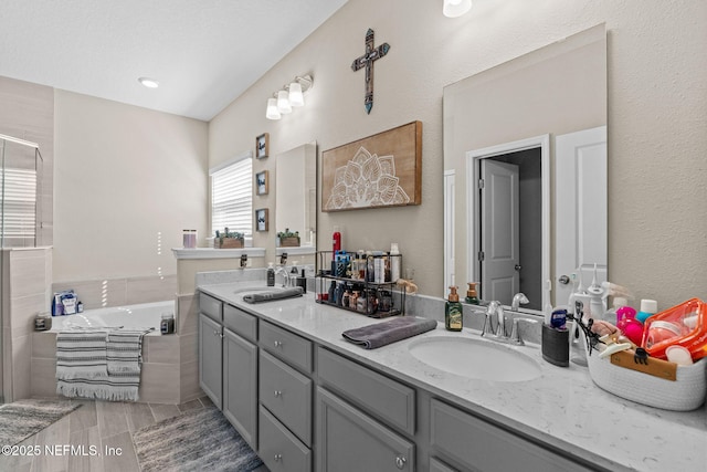 bathroom with vanity and tiled bath