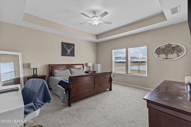 carpeted bedroom featuring a raised ceiling, ceiling fan, and a textured ceiling