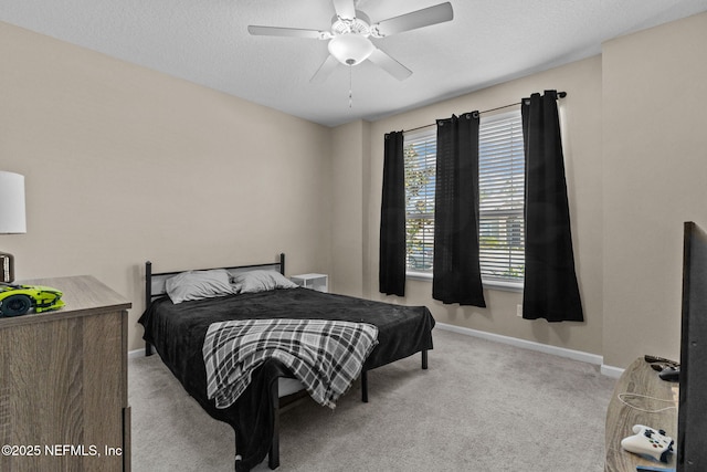 bedroom with ceiling fan, light colored carpet, and a textured ceiling