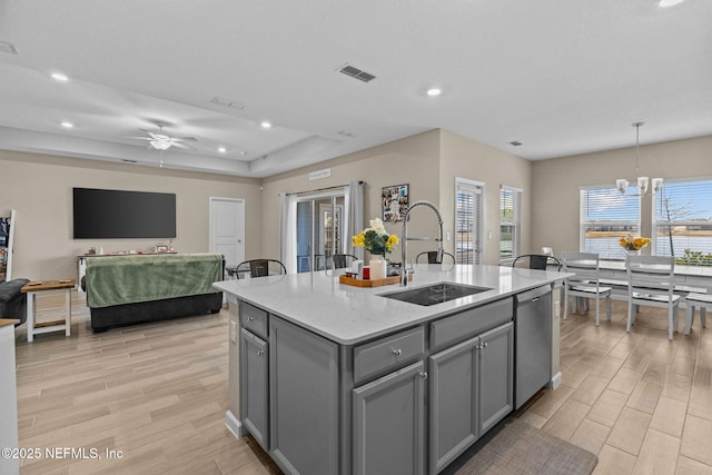 kitchen with gray cabinets, pendant lighting, dishwasher, sink, and a center island with sink