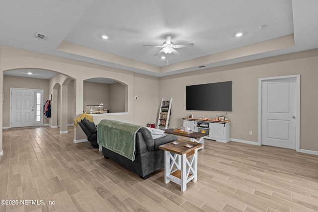 living room with ceiling fan and a tray ceiling