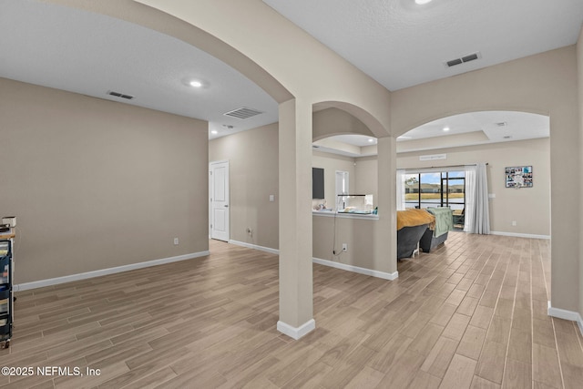 interior space with a tray ceiling and light hardwood / wood-style flooring