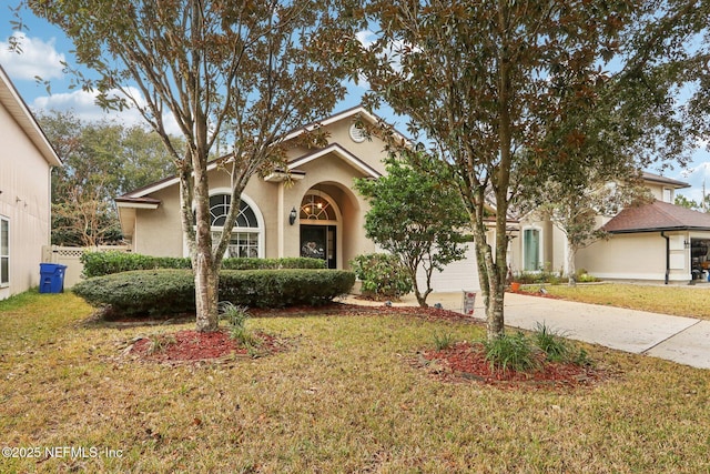 view of front of property featuring stucco siding, concrete driveway, and a front yard