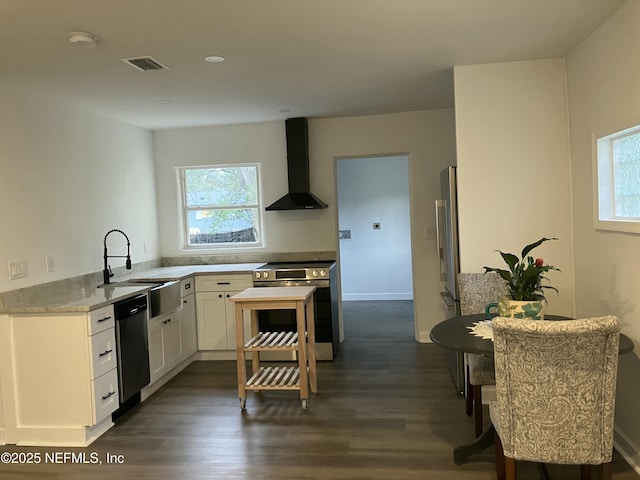 kitchen with wall chimney range hood, sink, dark wood-type flooring, appliances with stainless steel finishes, and white cabinets