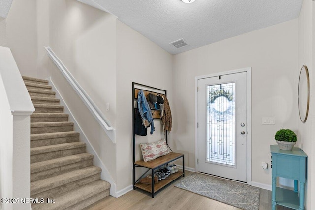 foyer featuring light hardwood / wood-style flooring and a textured ceiling