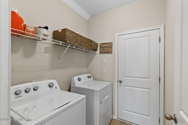 clothes washing area with separate washer and dryer and a textured ceiling