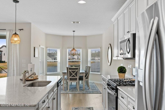 kitchen with sink, stainless steel appliances, white cabinetry, and light stone counters